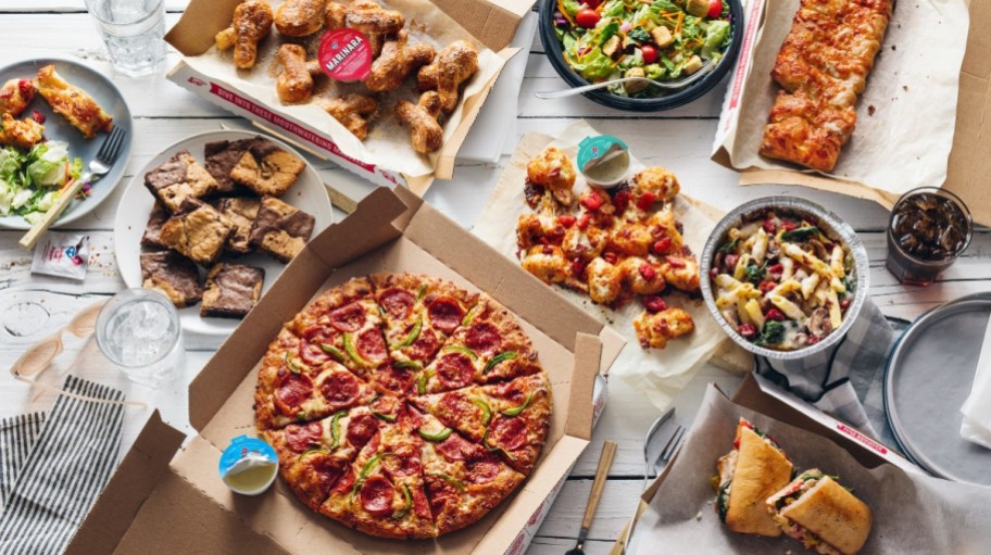 Domino's pizza, brownies, wings, salad and more laying on table