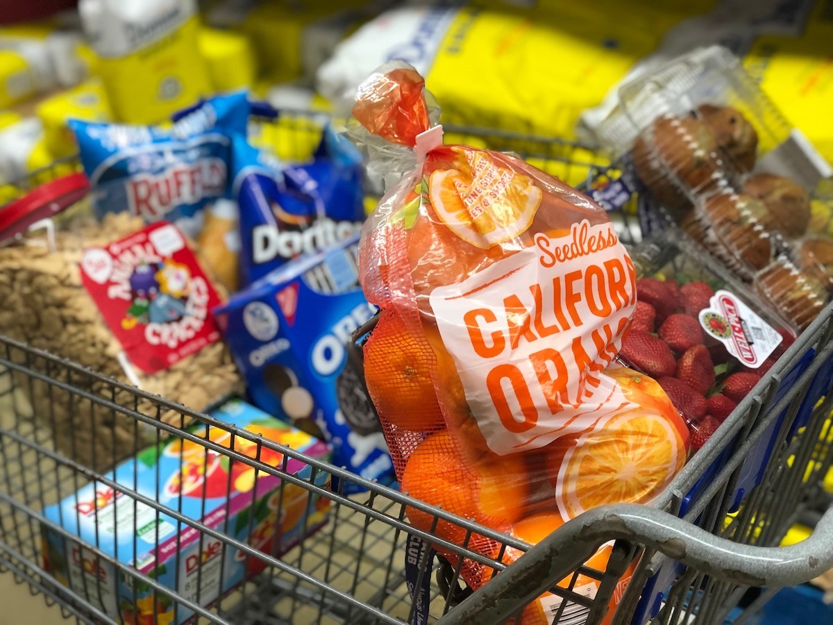 cart full of groceries with oranges strawberries muffins and other snacks