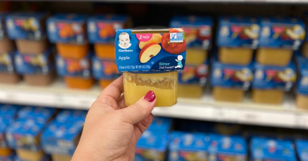 hand holding tub of baby food by store display