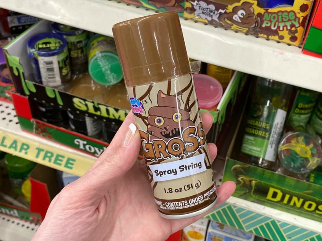 hand holding brown can of silly string by store display