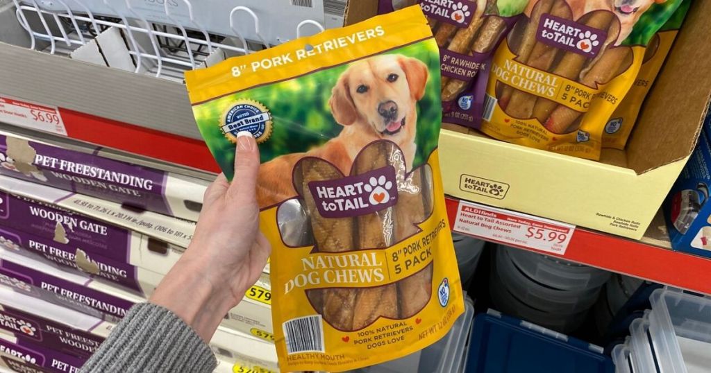 woman's hand holding package of dog treats at the store
