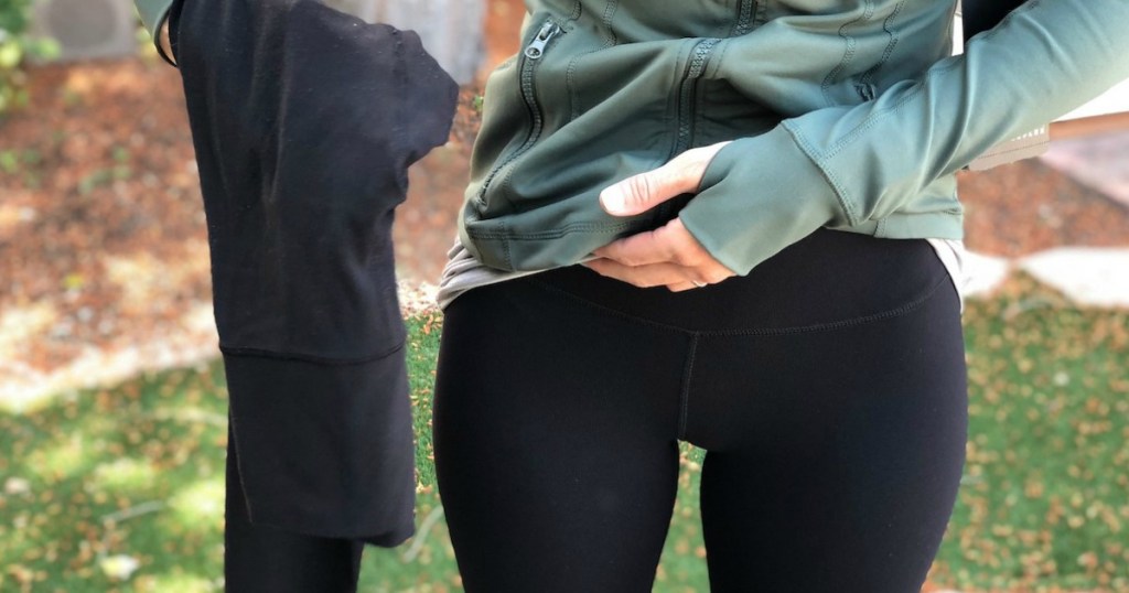 woman wearing black leggings holding black pair of leggings 