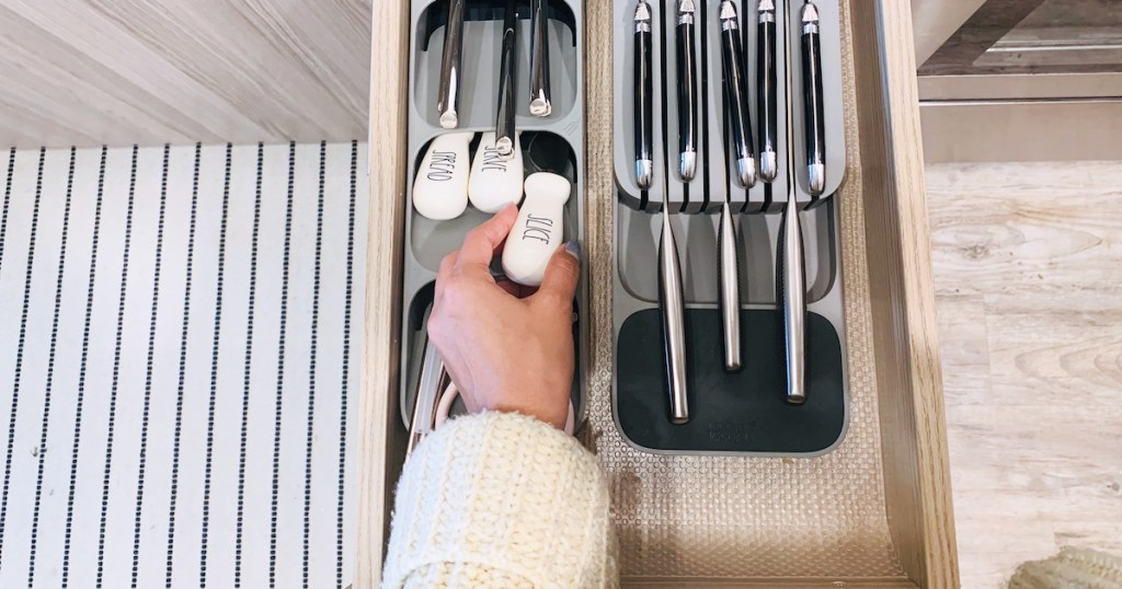 hands holding a white spreading knife in kitchen drawer