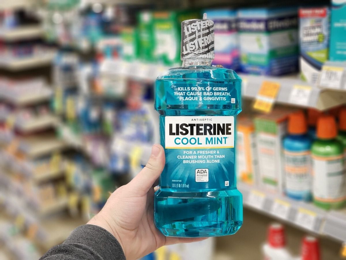 human hand holding listerine mouthwash bottle in store
