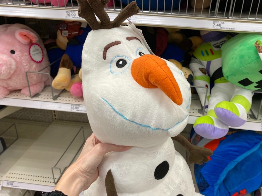 hand holding plush snowman by store shelves