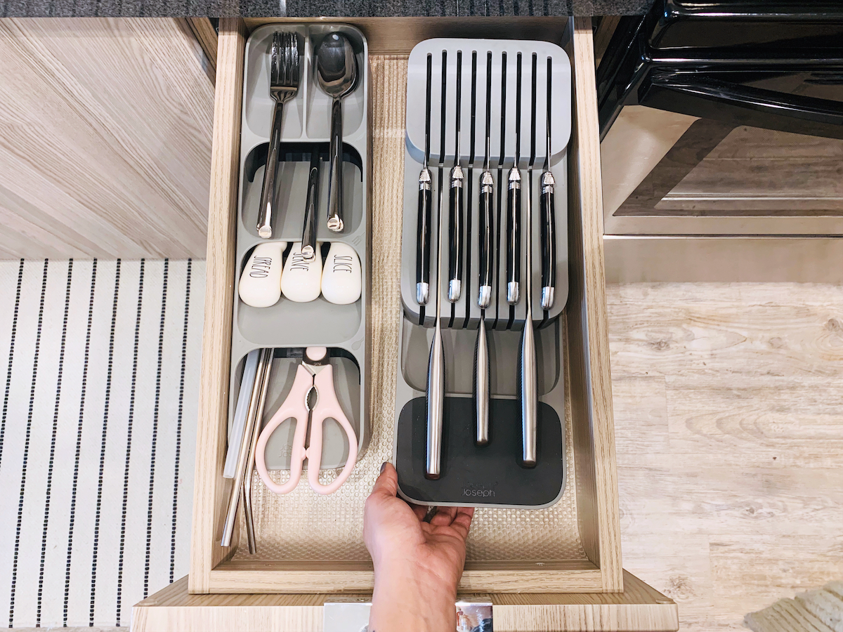 Hand holding a gray knife drawer organizer