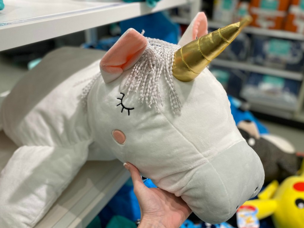 hand on head of stuffed unicorn on store shelf