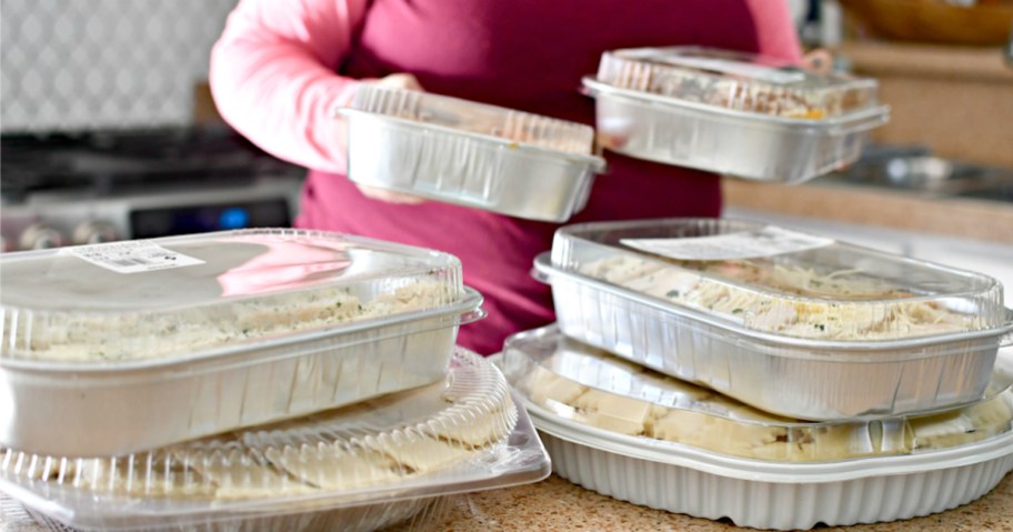 woman holding prepared meals in foil containers