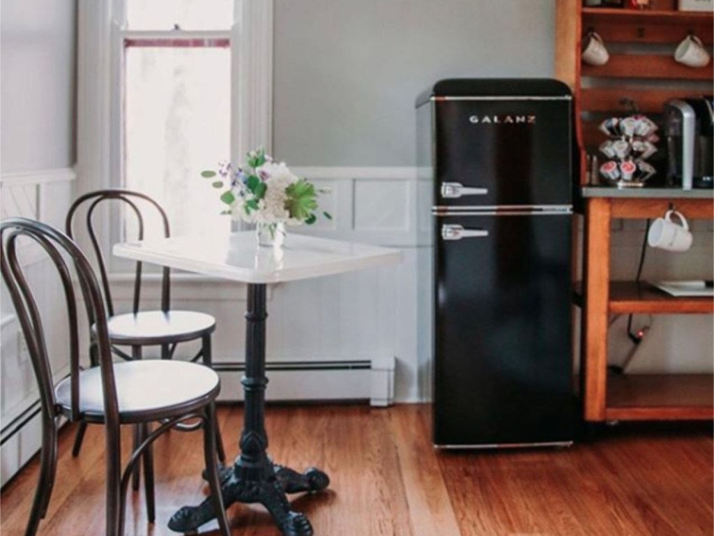 Galanz black retro refrigerator in kitchen with tiny table and two chairs in kitchen