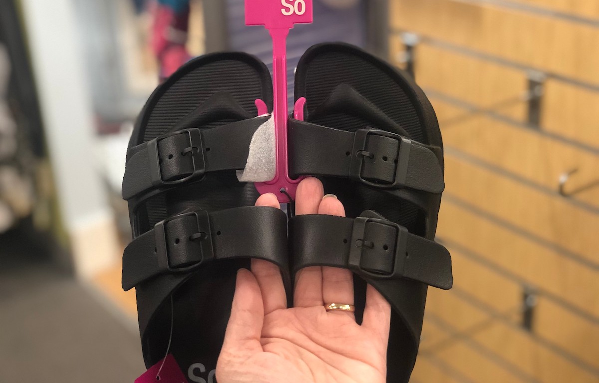 hand holding a pair of black sandals 