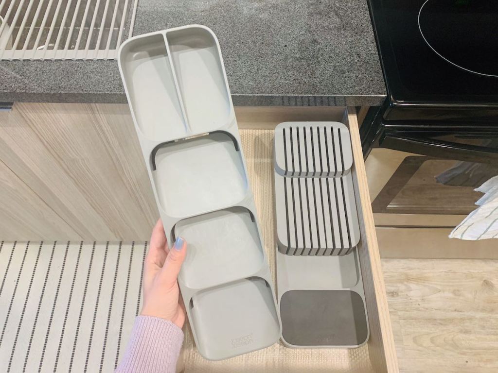 hand holding a gray silverware drawer organizer in kitchen