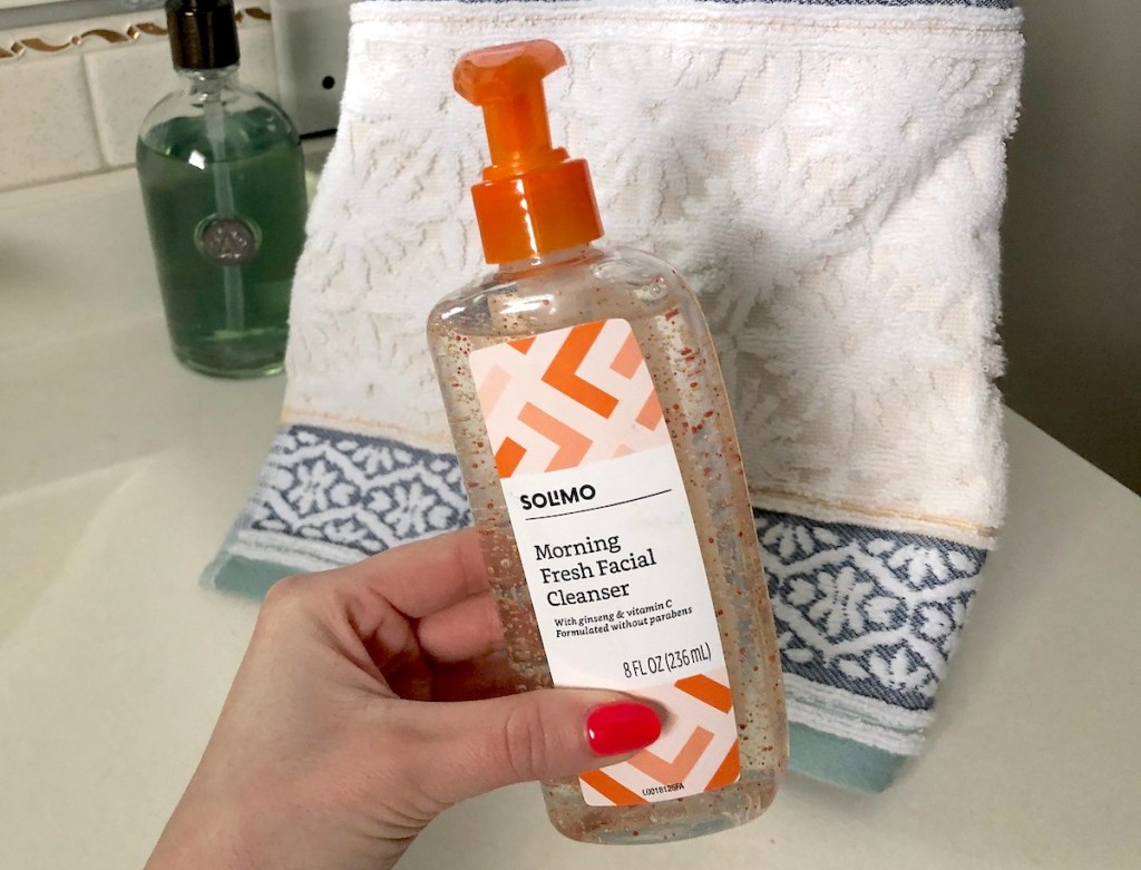 hand holding a bottle of orange bead facial cleanser