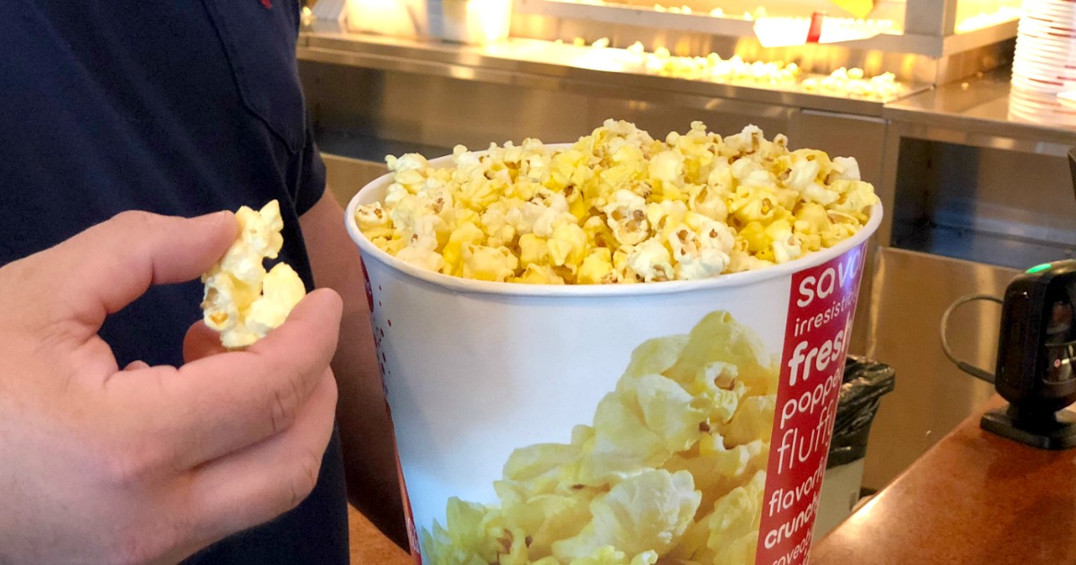Hand grabbing popcorn from movie theater popcorn bucket