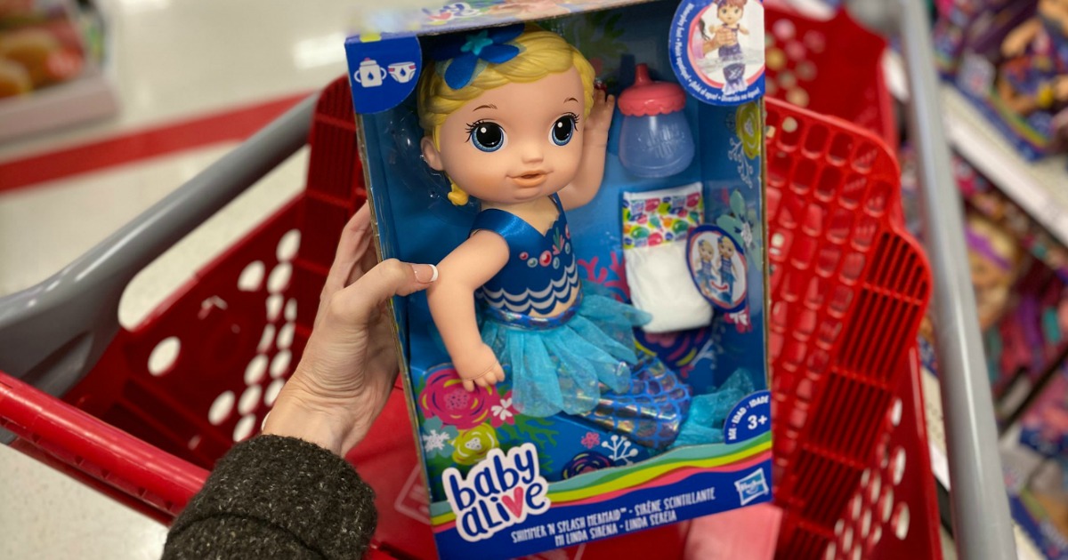 Woman holding a mermaid-themed baby alive mermaid doll in-store near a red shopping cart
