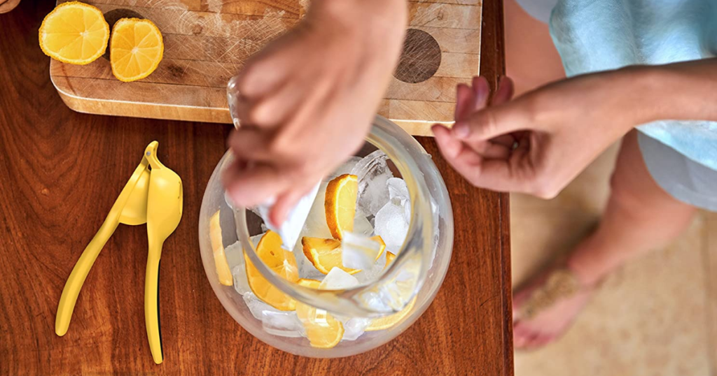 Woman standing over counter making lemonade with citrus squeezer 