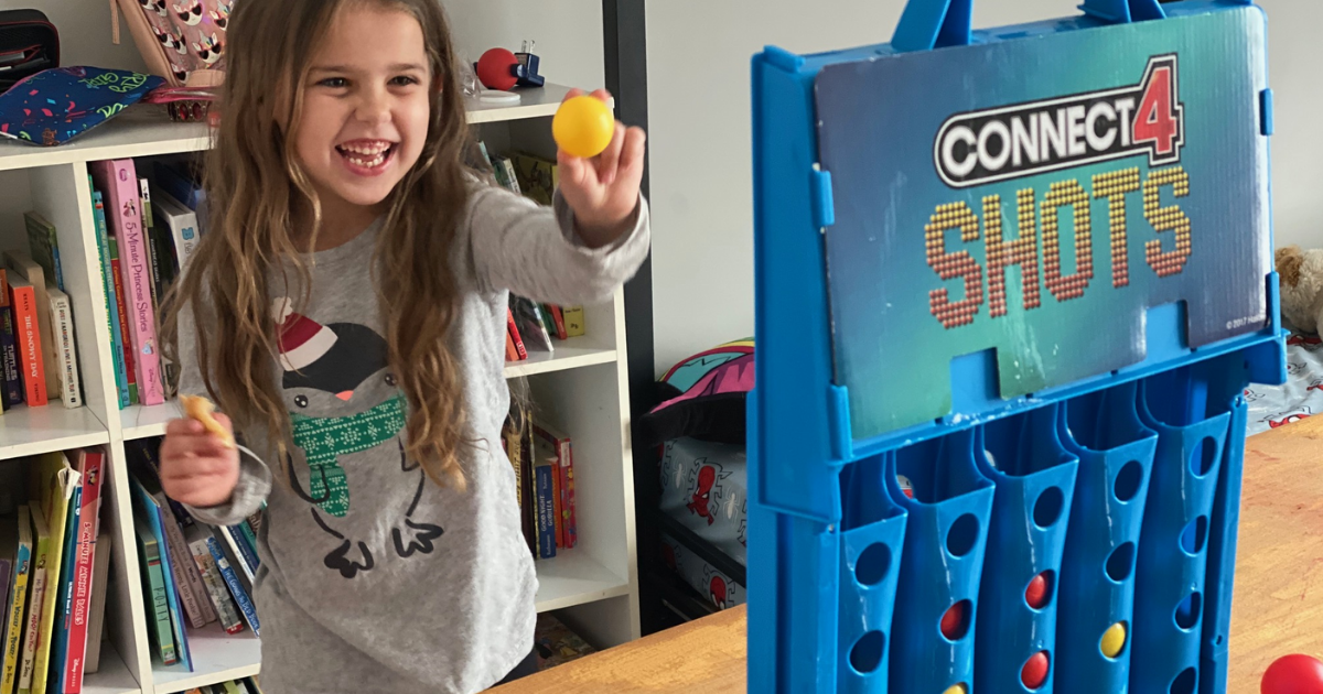 Little girl shooting ball into Connect 4 Shots game