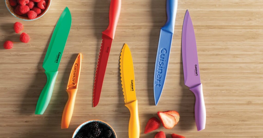 Large colorful knife set on wooden surface near berries