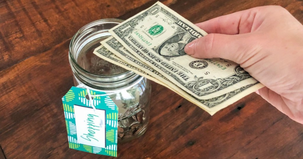 putting dollar bills in jar 
