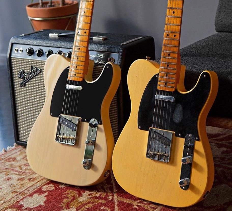 two Fender guitars leaning on an amp