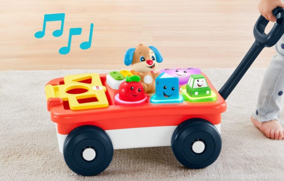 young child playing with and rolling toy wagon
