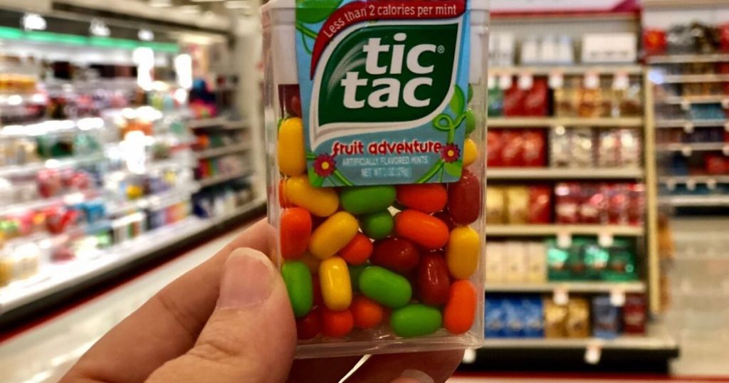 womans hand holding package of fruity tic tacs in store