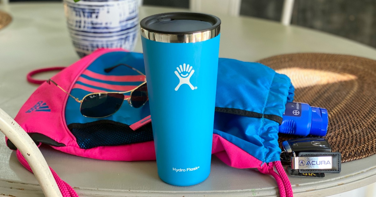 Hydro Flask tumbler next to sunglasses and sports bag