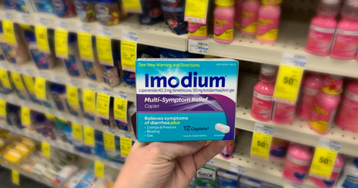 Hand holding Imodium in front of shelf 