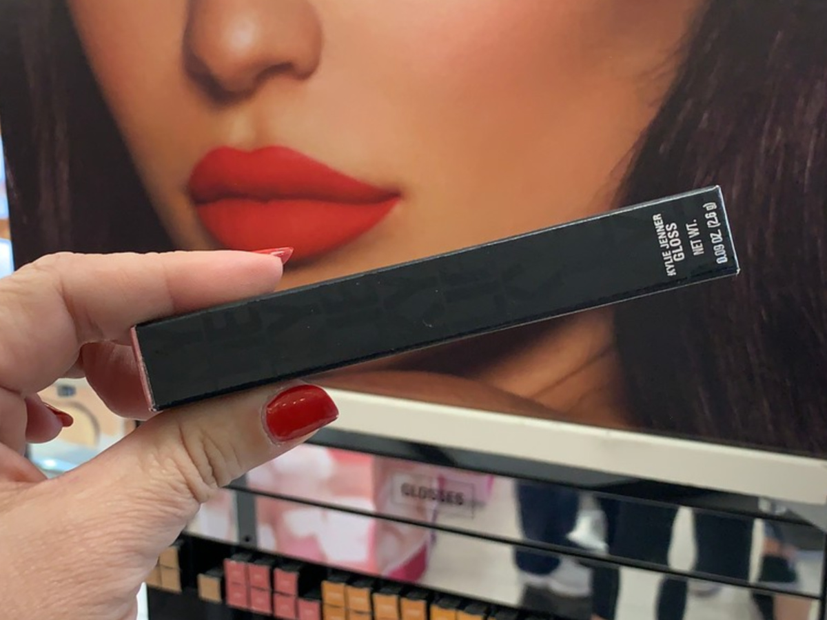 woman's hand holding lip gloss in makeup store