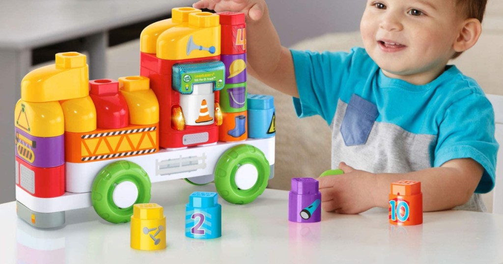 young boy playing with truck toy set