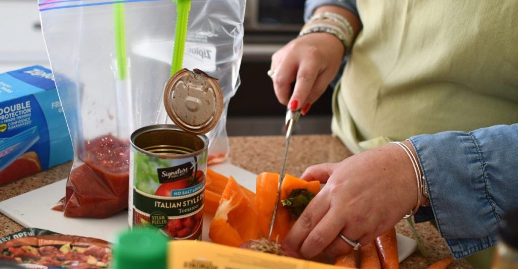 Woman cutting a pepper as part of doing a weekly meal prep of easy Crock Pot freezer meals