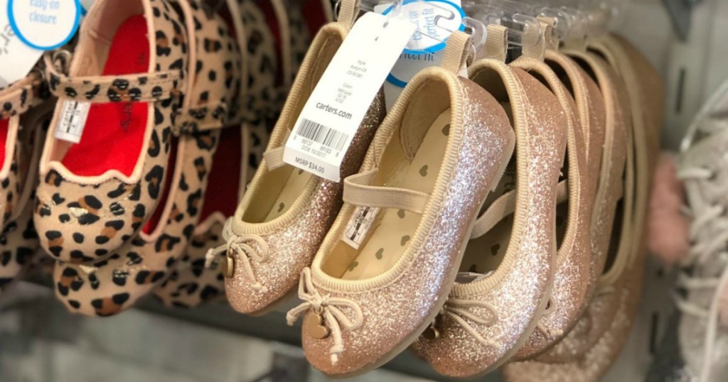 Pairs of slip on baby girls shoes on hangers on in-store rack