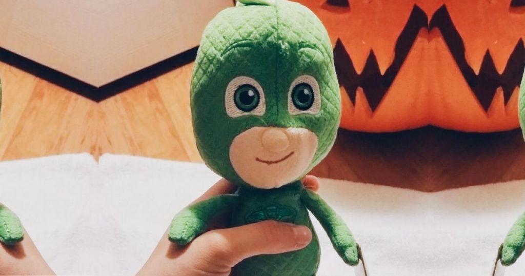human hand holding small plush toy of Gekko from PJ Masks