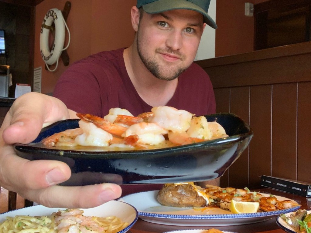 man holding plate of shrimp to show camera