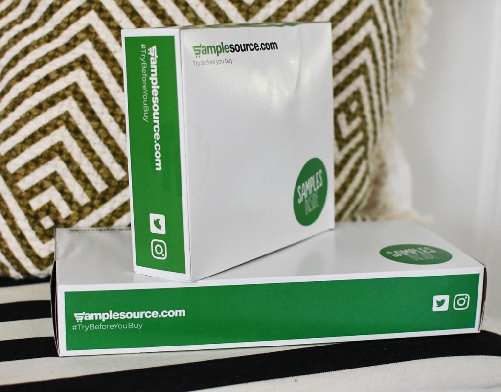 green and white samplesource boxes stacked next to a throw pillow