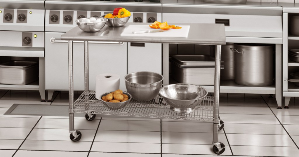 stainless steel work table in kitchen, with pots and pans, food, etc. on shelves