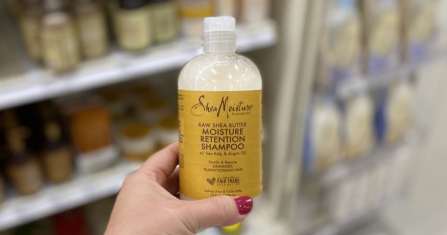 woman hand holding up SheaMoisture Raw Shea Butter Moisture Retention Shampoo in target
