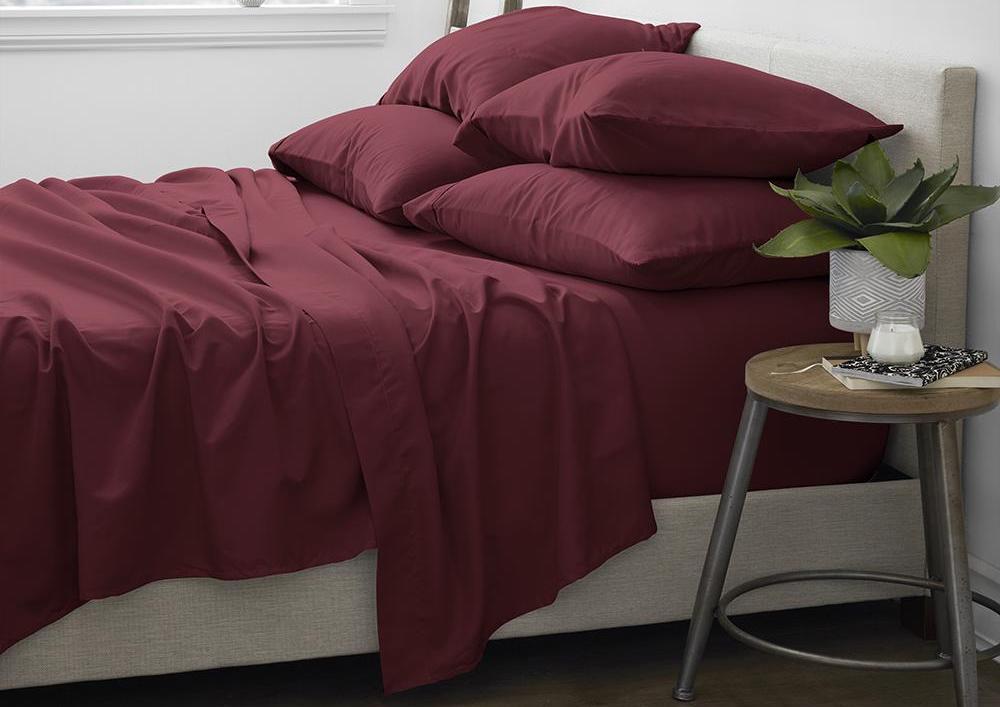 bed with maroon sheets on it