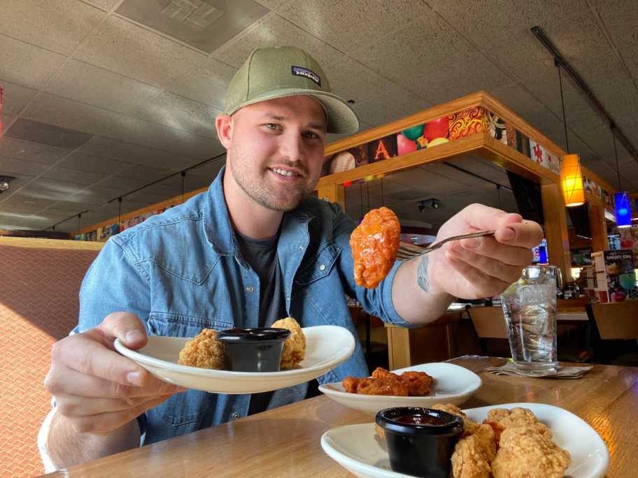man sitting at a table eating wings 