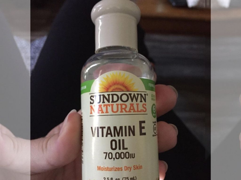 woman's hand holding bottle of vitamin E oil