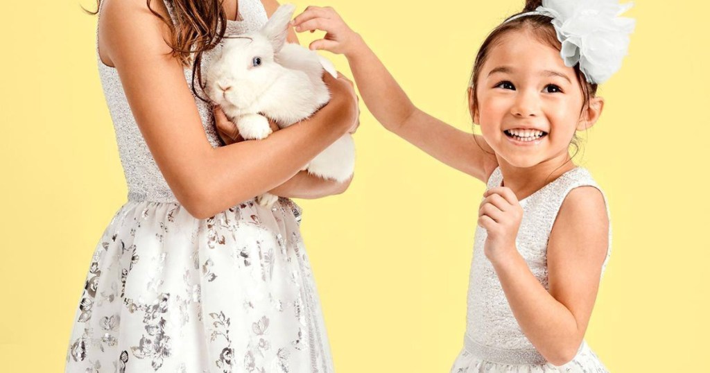 Two young girls in dresses holding a bunny