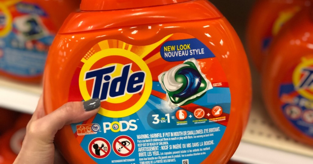 woman's hand holding laundry detergent pac container in store aisle