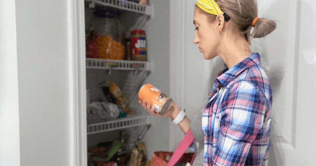 Woman looking for food items in pantry and holding a can