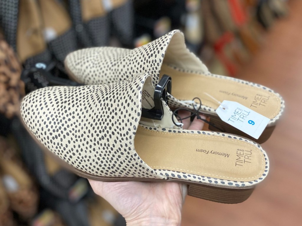 hand holding women's black patterned mule in store aisle