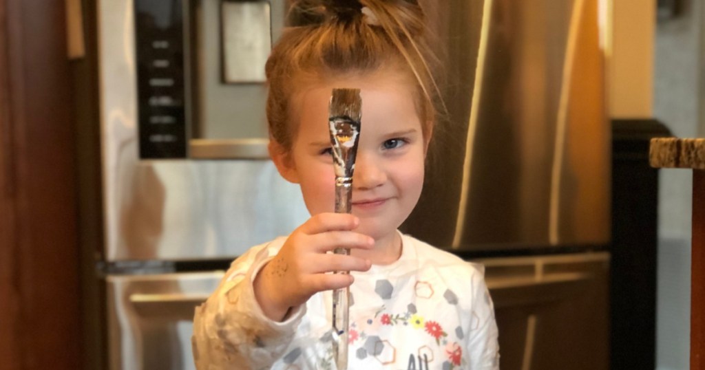 Young Girl Holding Paintbrush in kitchen