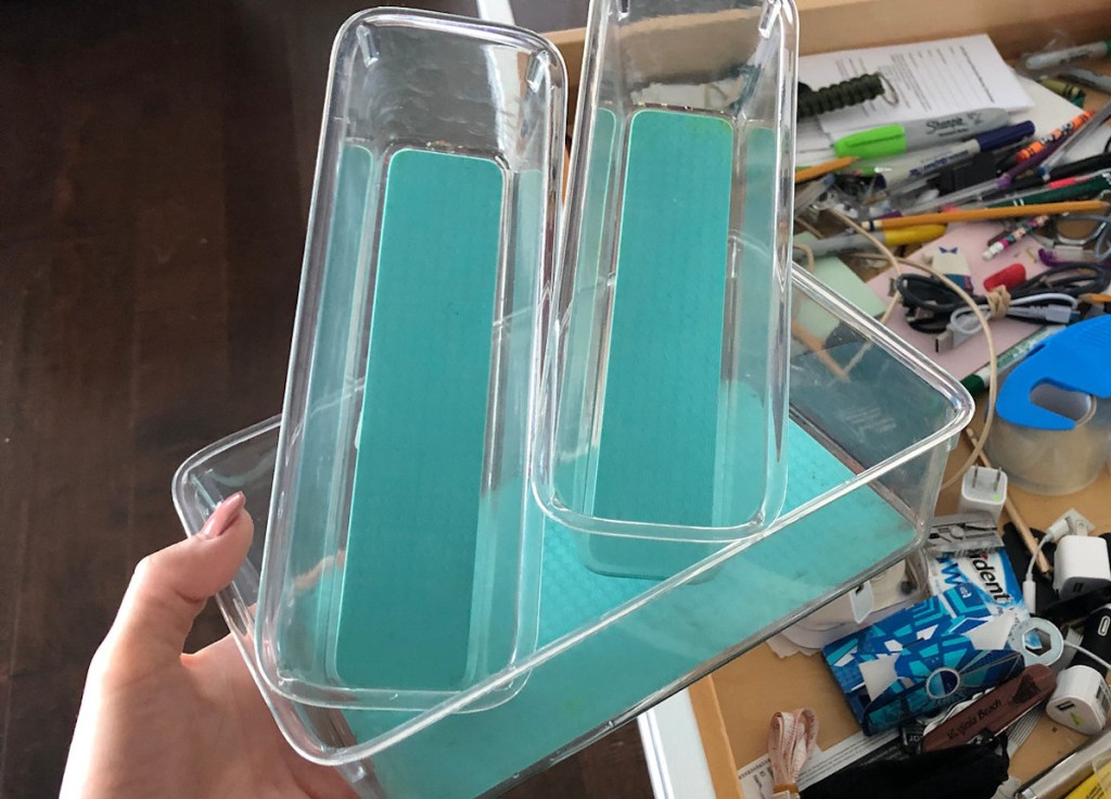 hand holding acrylic drawer organizers over messy junk drawer