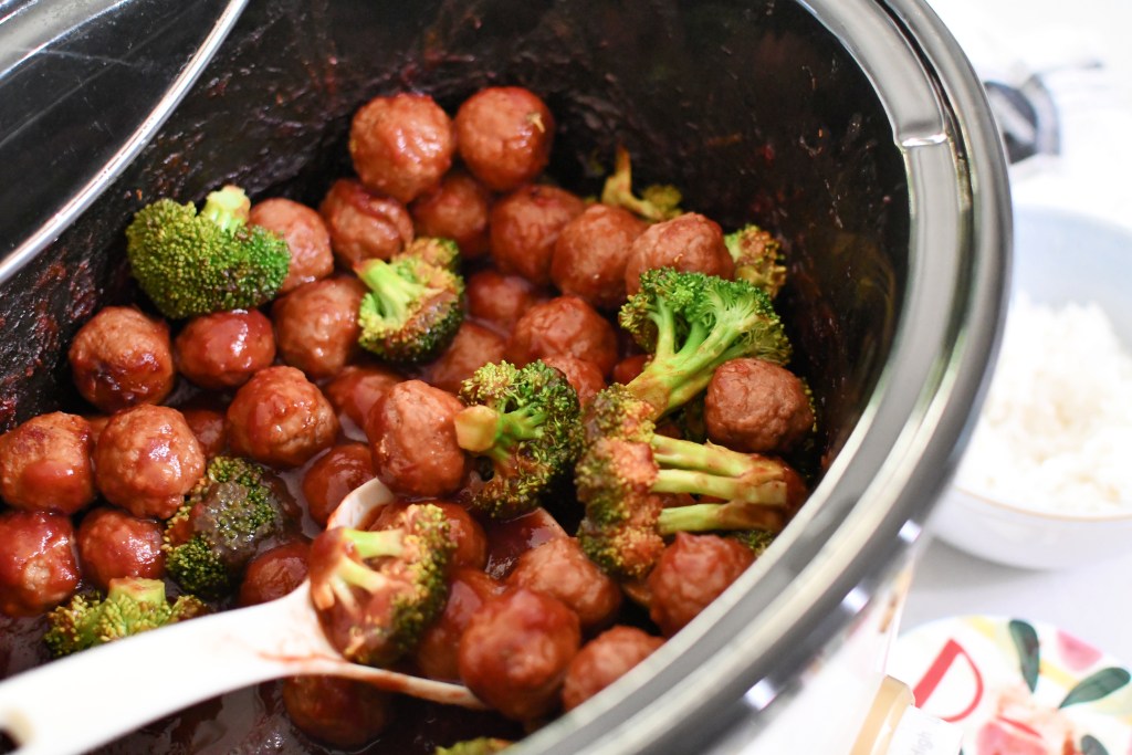 adding fresh broccoli to cranberry slow cooker meatballs