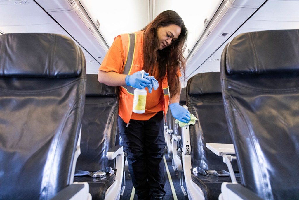woman cleaning seatrests on plane