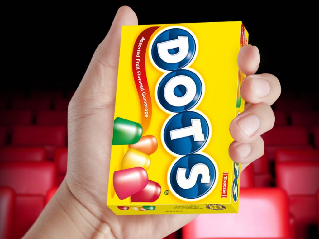 hand holding box of dots with movie theater chairs in background