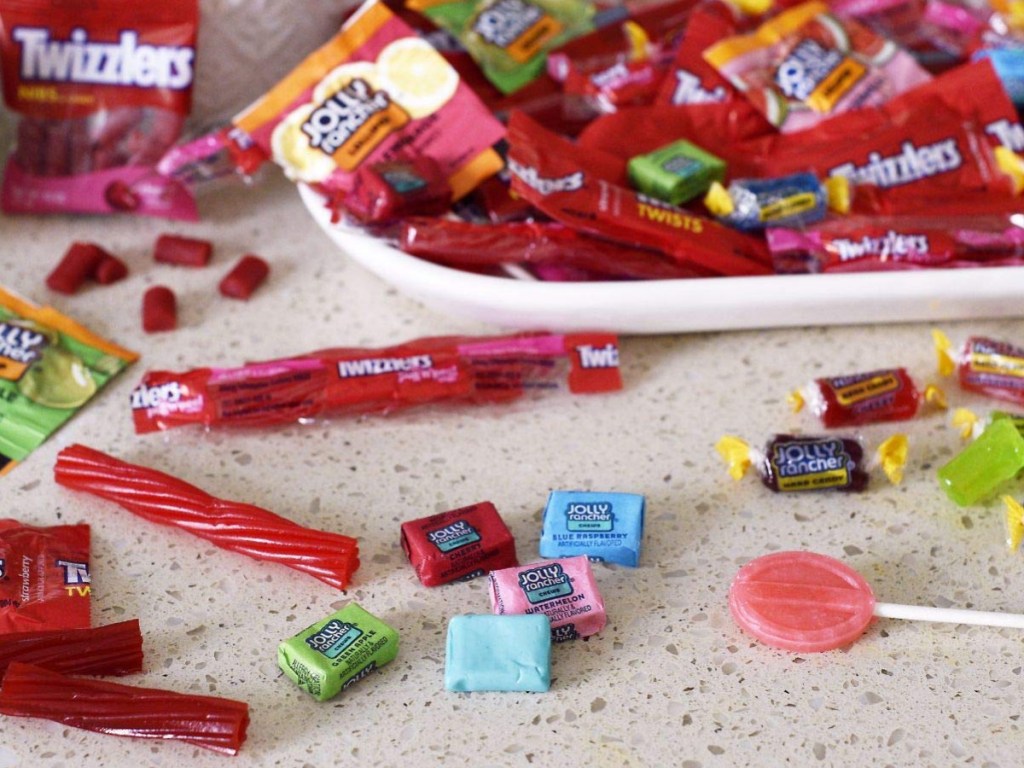 Twizzlers, jolly ranchers and suckers on white dish and scattered