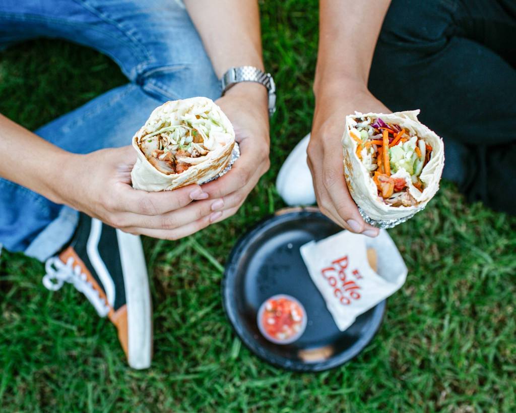 overhead view of two people eating burritos outside
